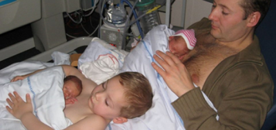 Padre y pequeño niño piel con piel con gemelos recién nacidos